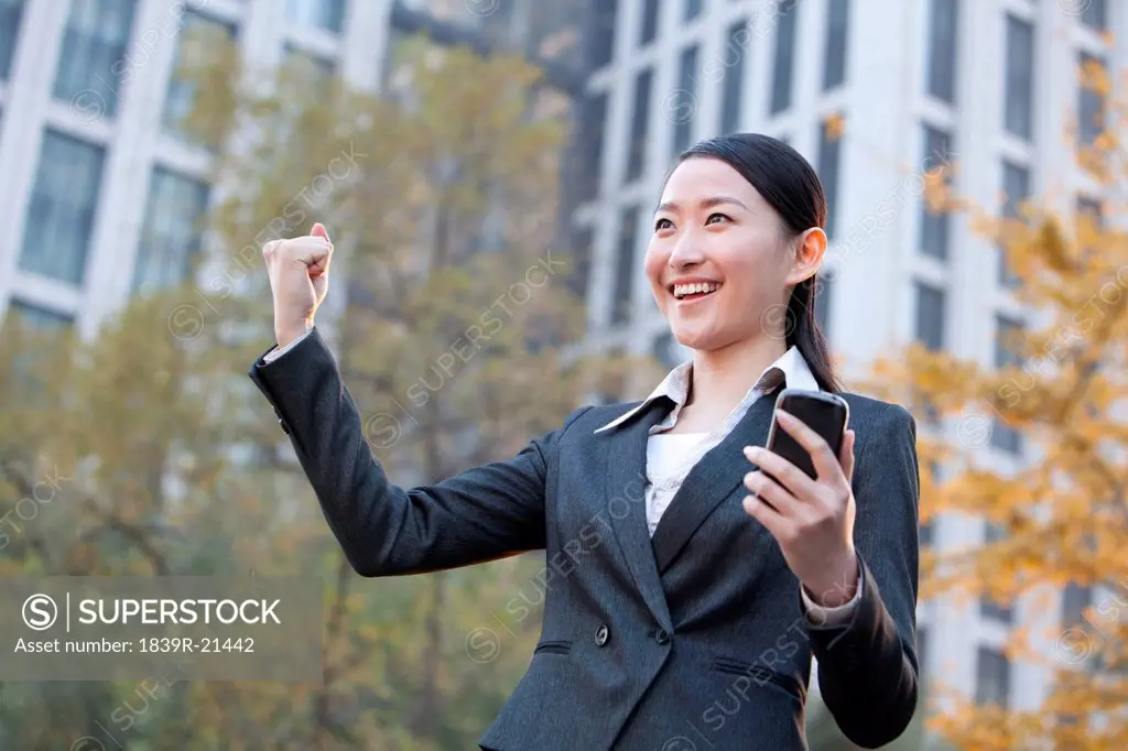 Businesswoman looking at her mobile phone and celebrating