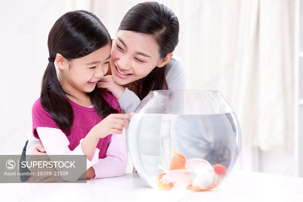 Mother and daughter having fun with goldfishes