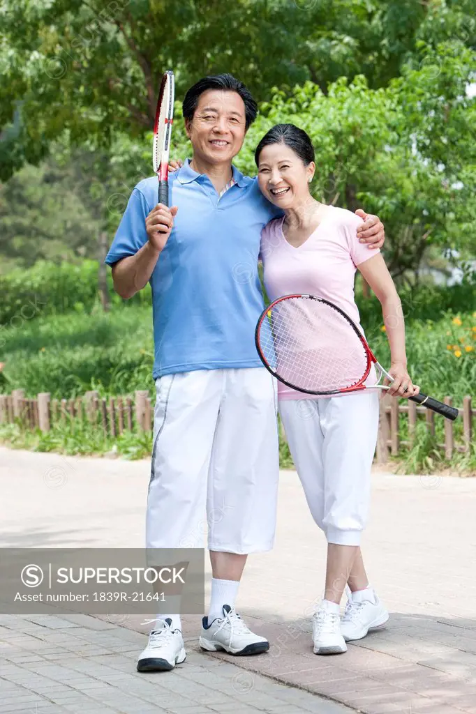Happy couple playing tennis in park