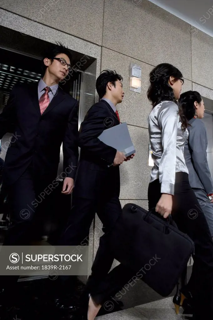 Businesspeople Walking Out Of Elevator