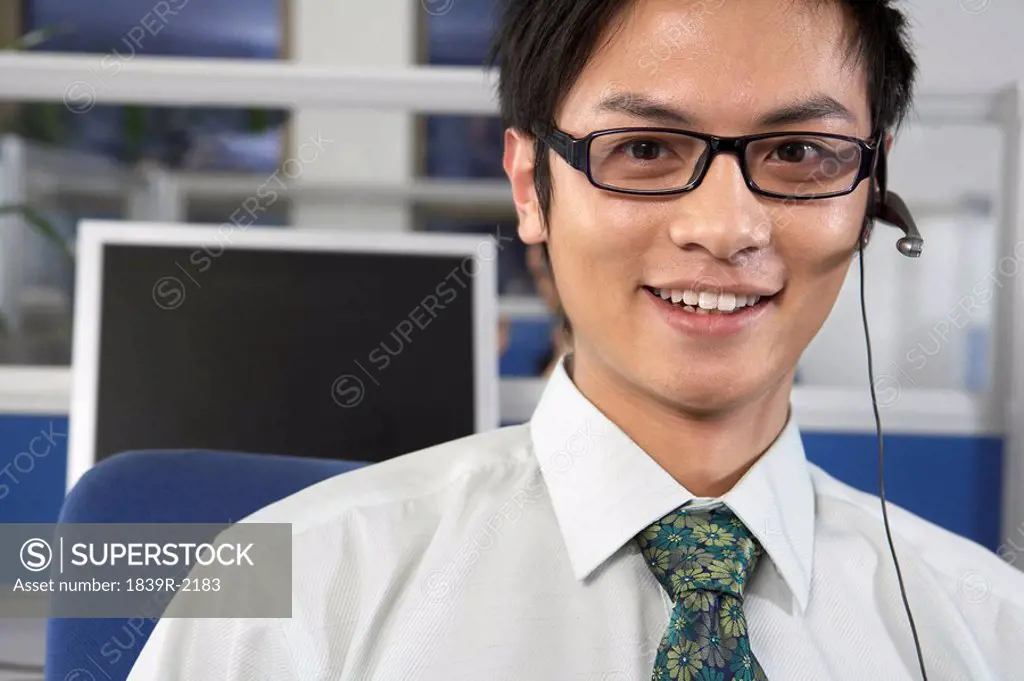 Man In Call Centre Wearing A Headset And Smiling