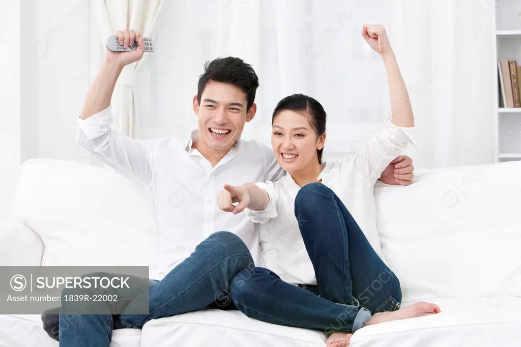 Happy young couple watching TV together