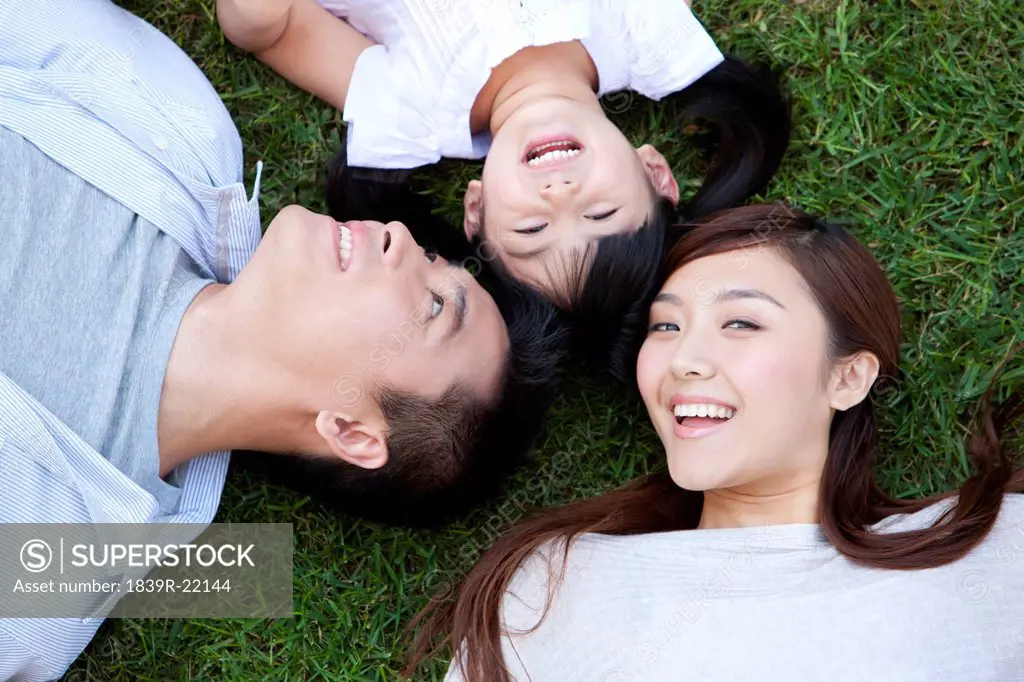 Young Chinese family lying on the grass