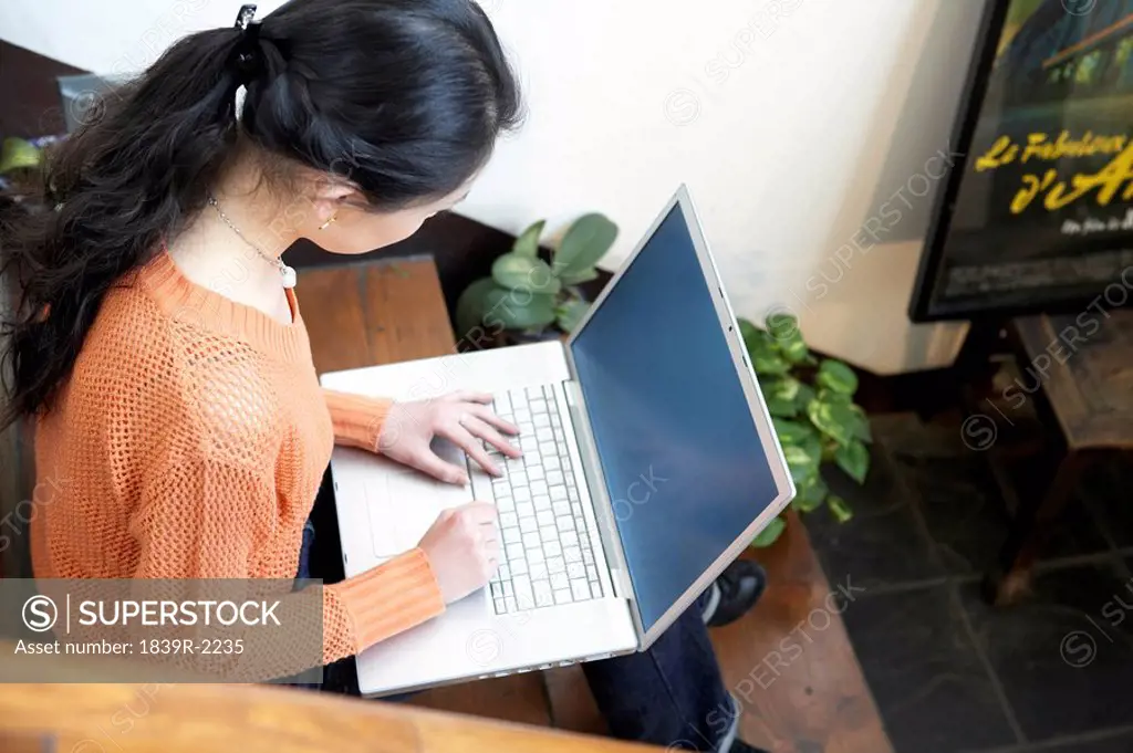 Young Woman Sitting On Staircase With Laptop Computer