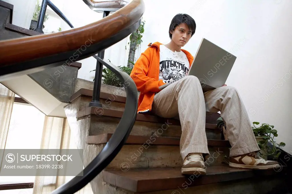 Young Man Sitting On The Stairs With Laptop Computer