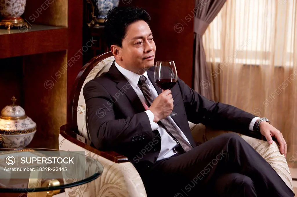 Mature businessman enjoying wine in a luxurious room