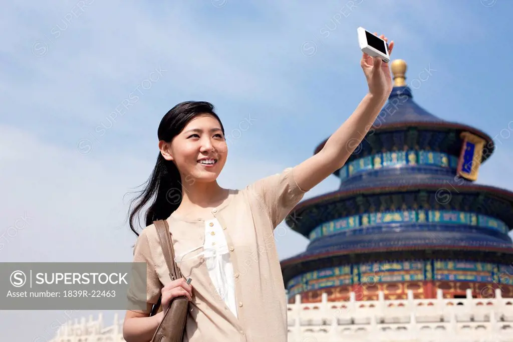 Young woman taking self_portrait at Temple of Heaven in Beijing, China
