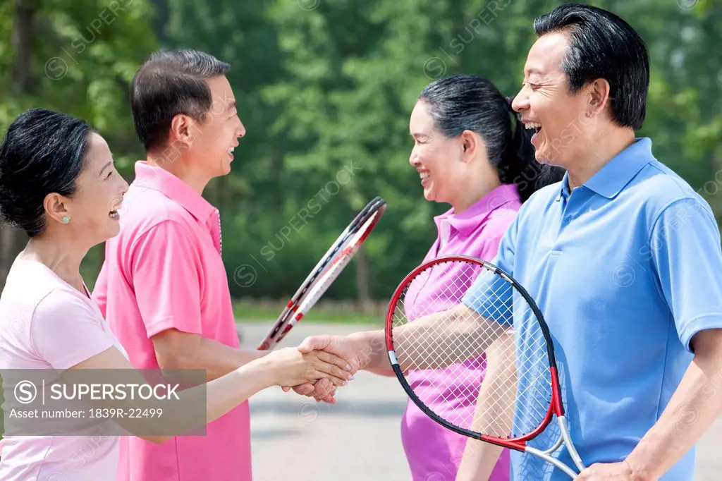 Senior couples playing tennis in park