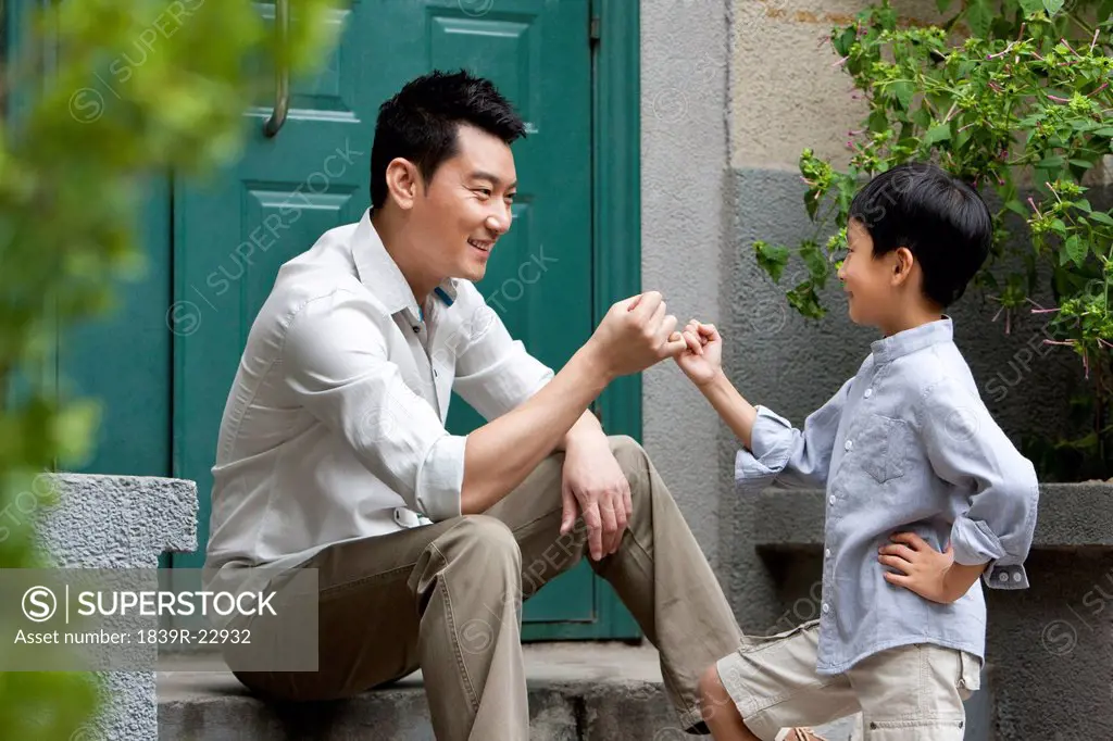 Young Chinese father and son on front stoop