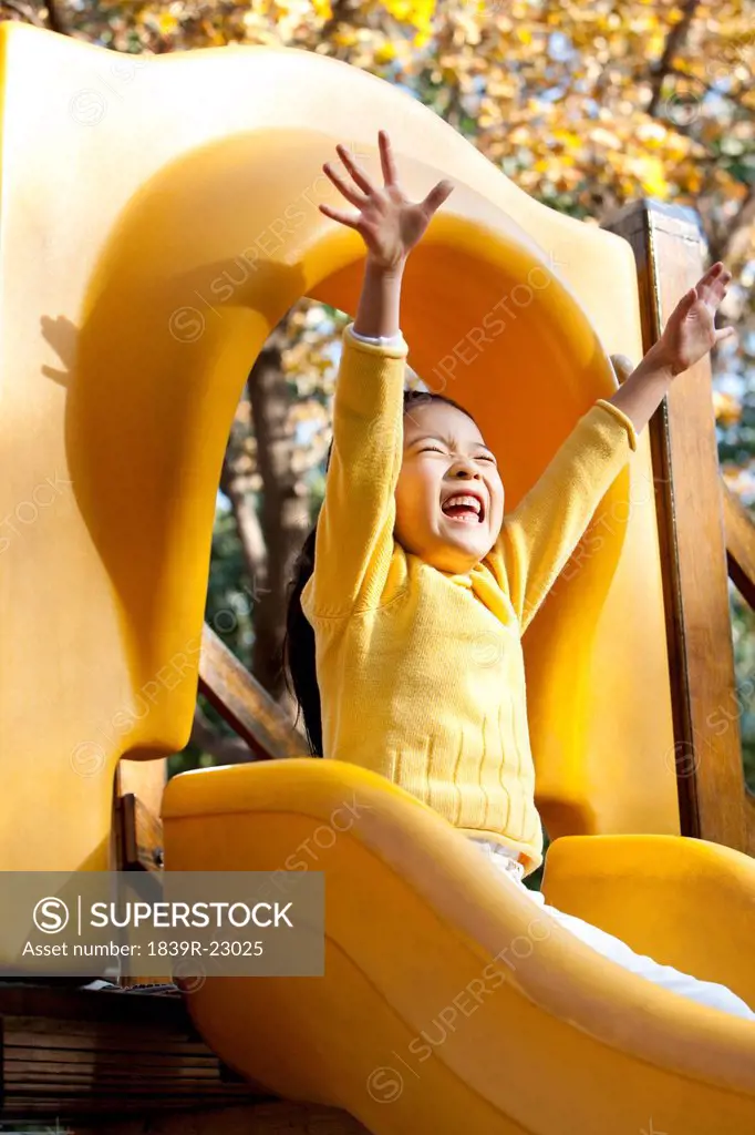 Esctatic girl playing on playground slide