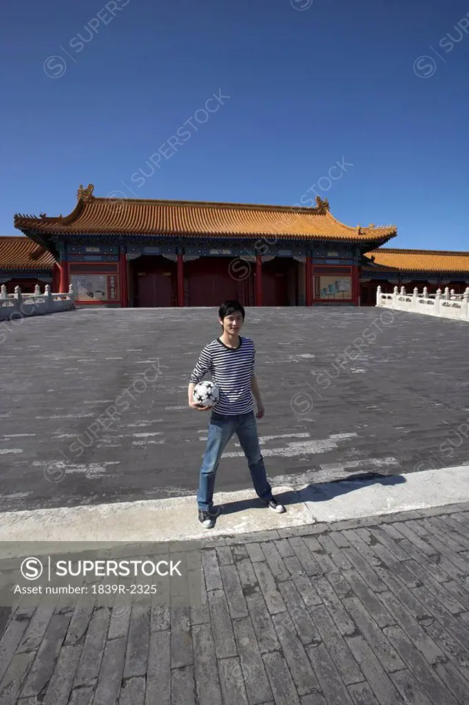 Young Man Holding Soccer Ball In Front Of The Forbidden City