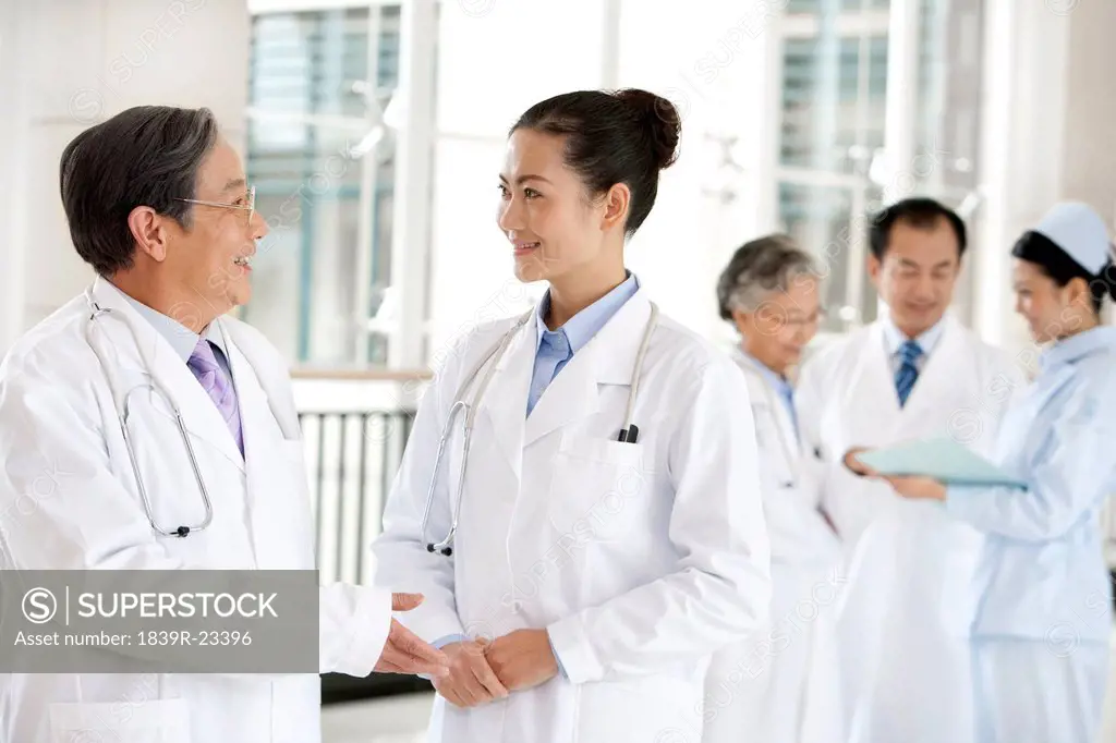 Doctors and and a Nurse in a Hospital Corridor in Discussion