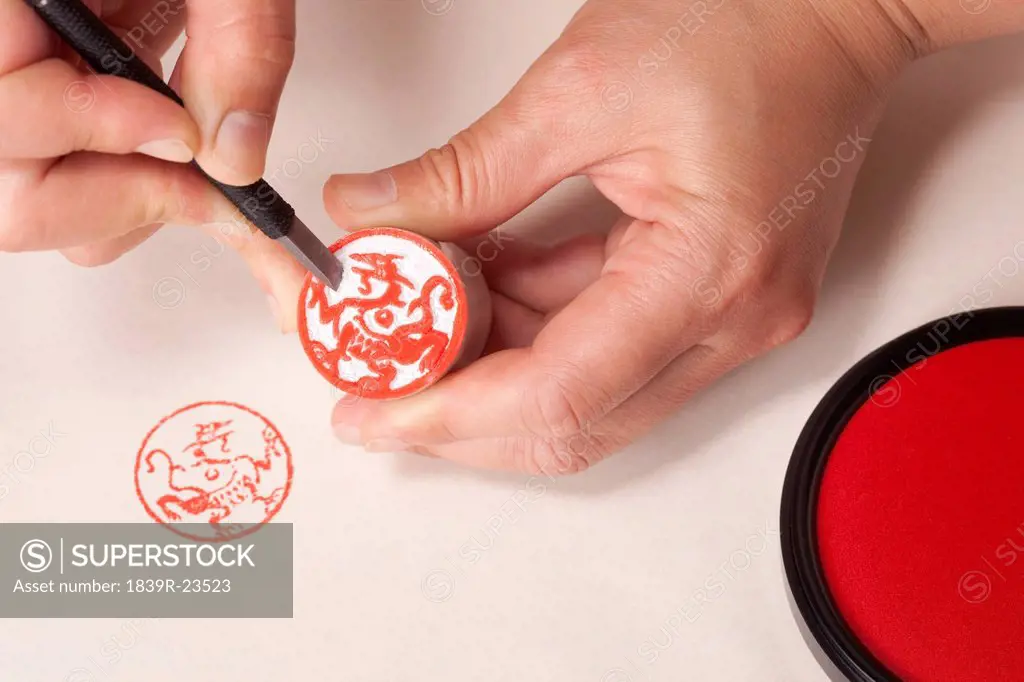 Hands carving a Chinese dragon stamp