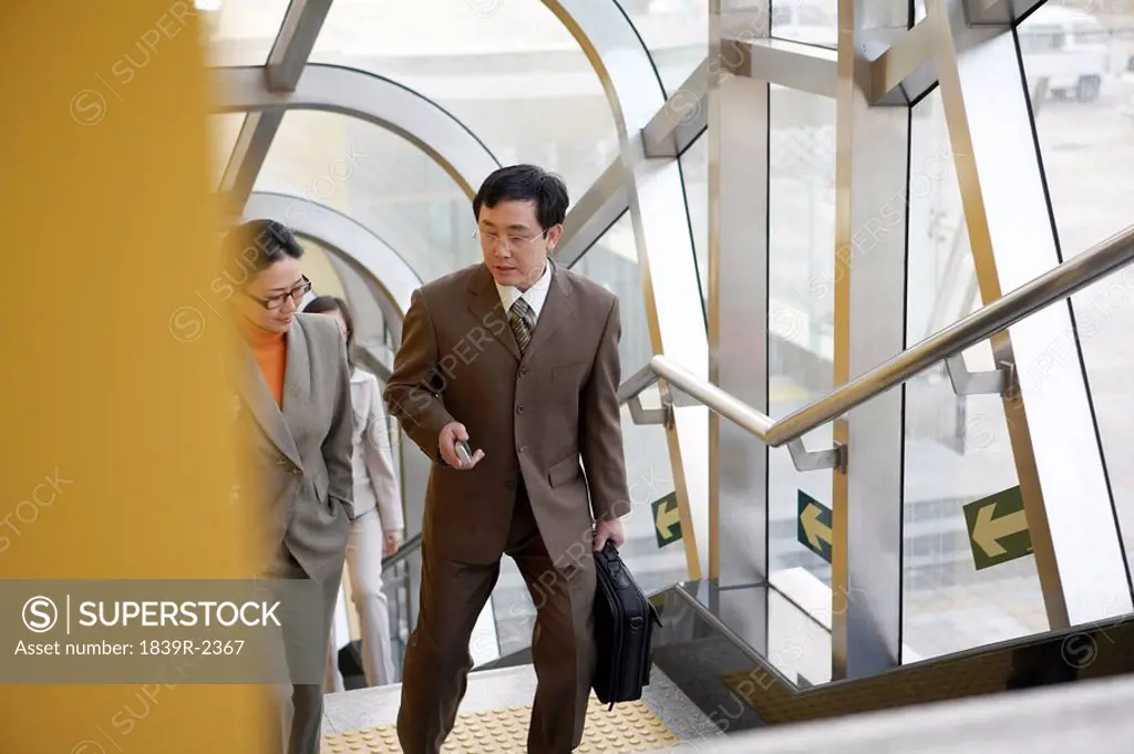 Businessman And Businesswoman Walking Up Subway Stairs