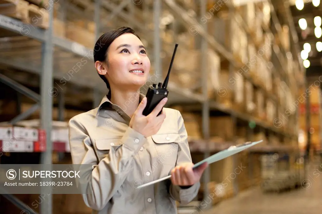 Female Chinese warehouse worker with clipboard and walkie_talke