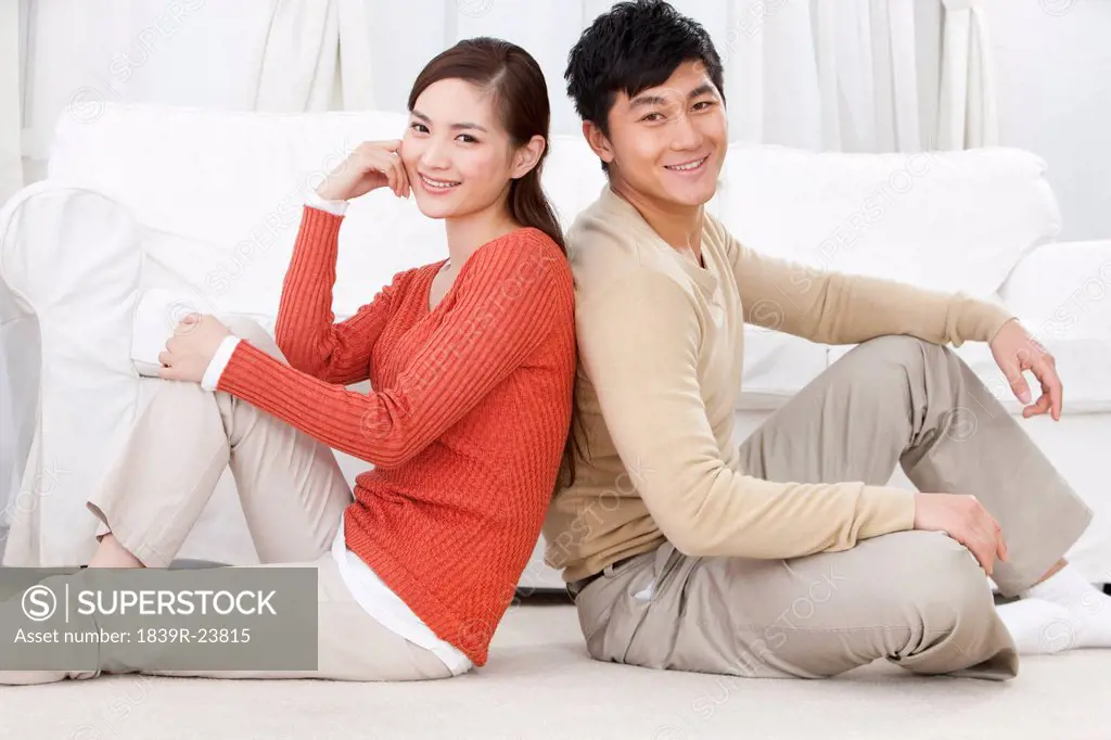 Happy young couple sitting on carpet