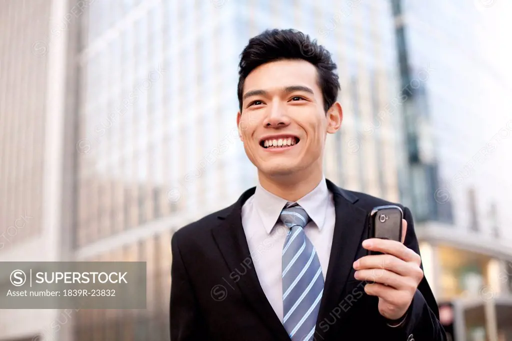 A businessman outside office buildings with his mobile phone
