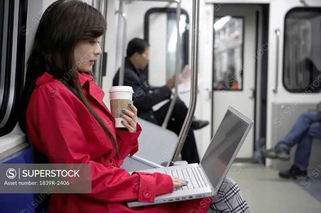 Woman Sitting On Train Typing On Laptop