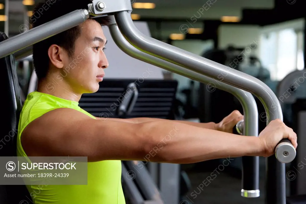 Young Man Using Exercise Machine