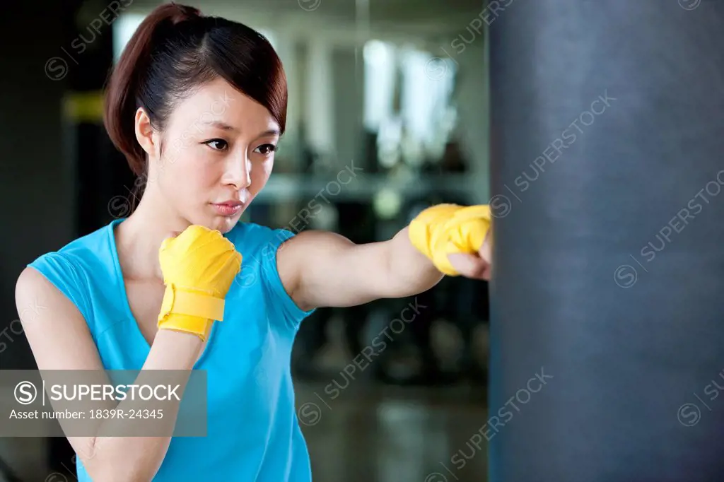 Young Woman in Hand Wraps Punching Punching Bag