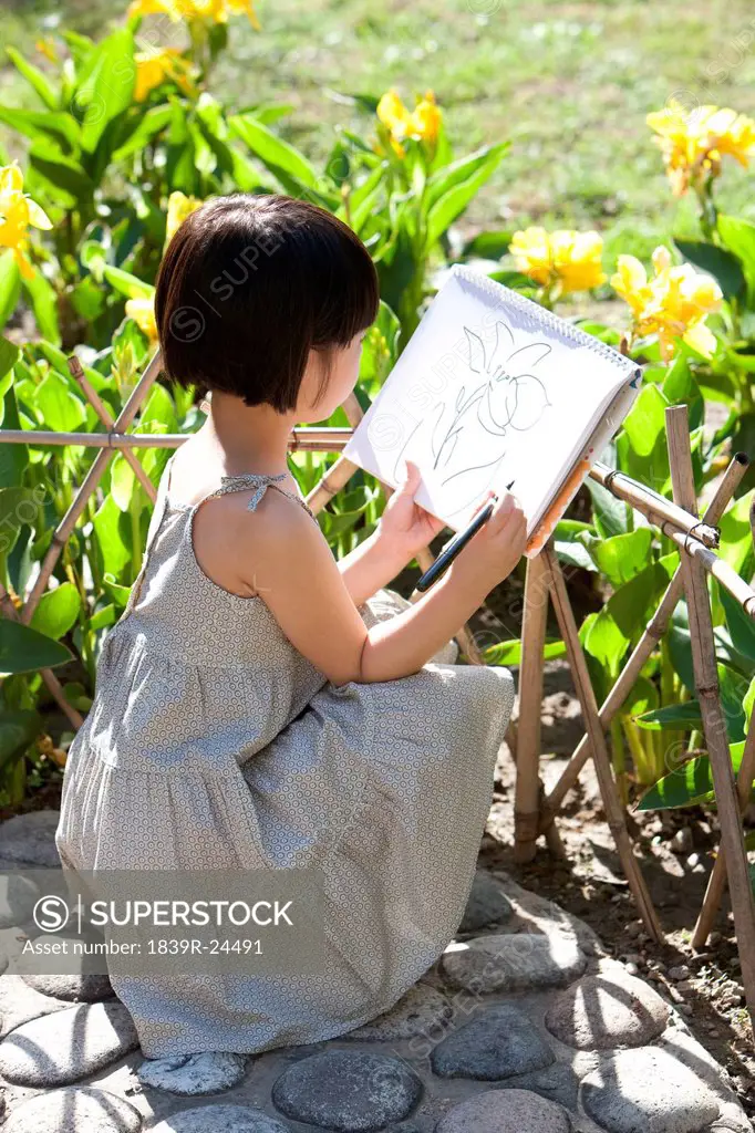 Little girl painting in garden