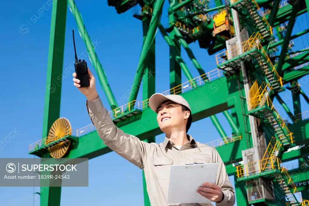 Male shipping industry worker with walkie_talkie pointing