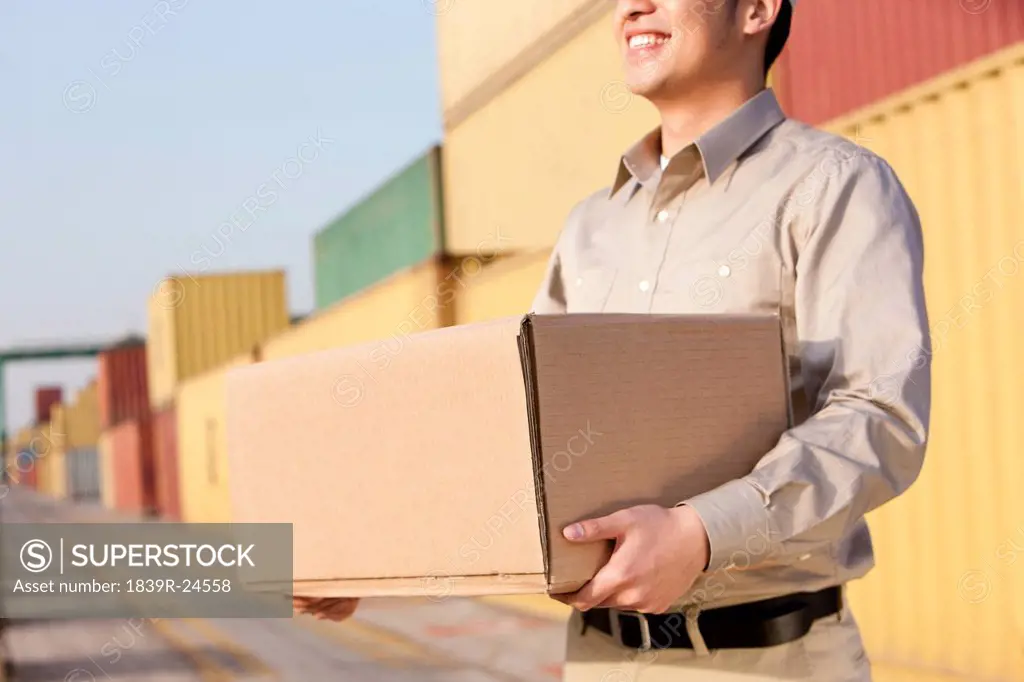 Shipping industry worker carrying a cardboard box