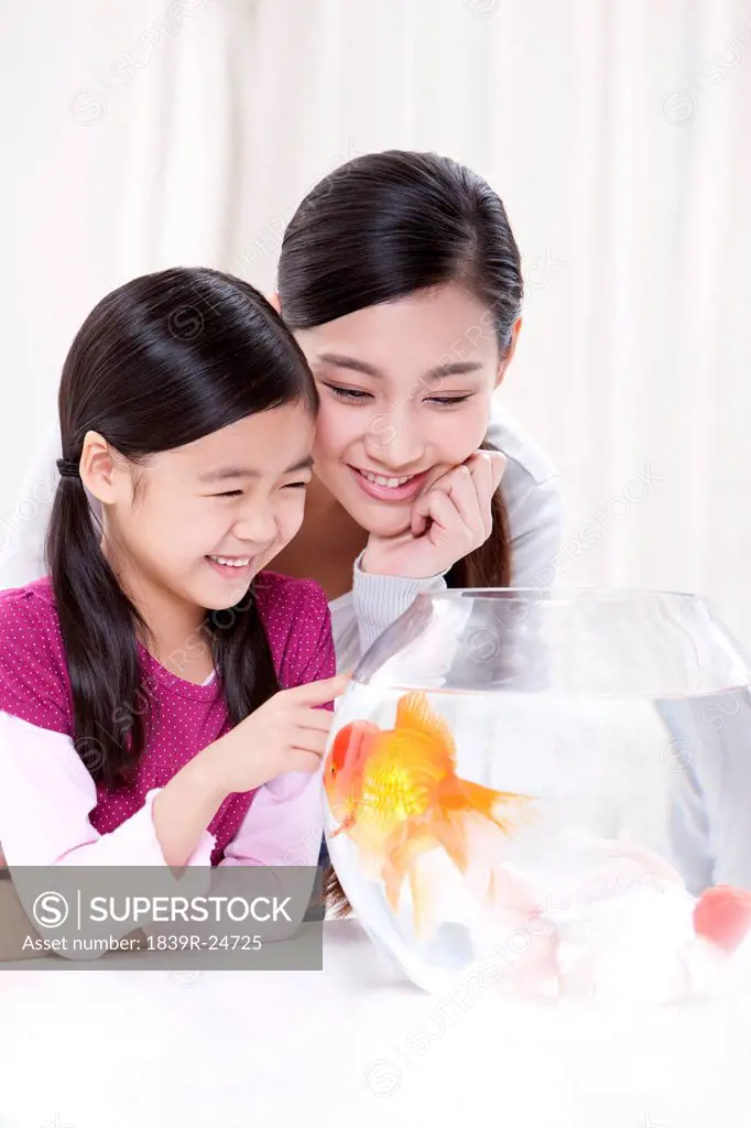 Monther and daughter having fun with goldfishes