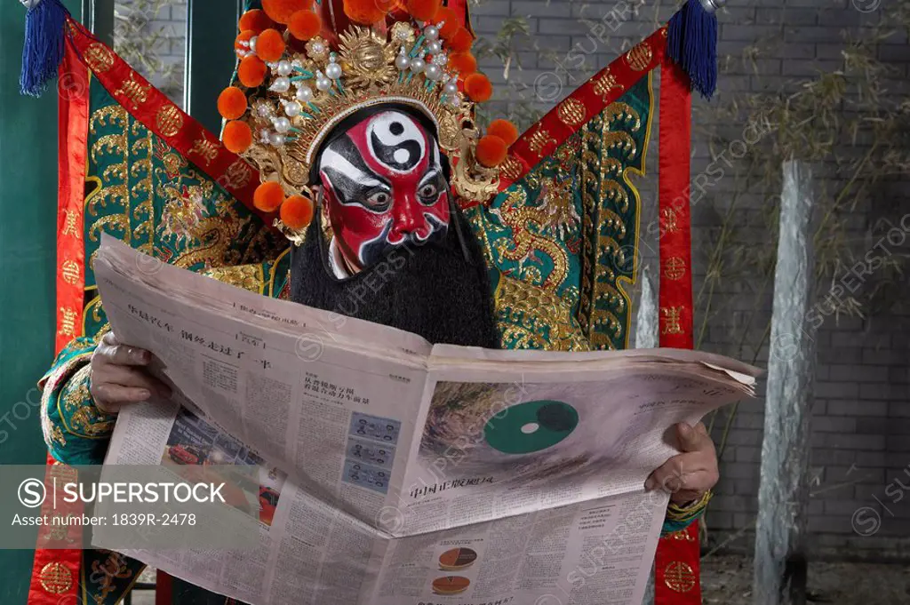Man In Ceremonial Costume Reading Newspaper