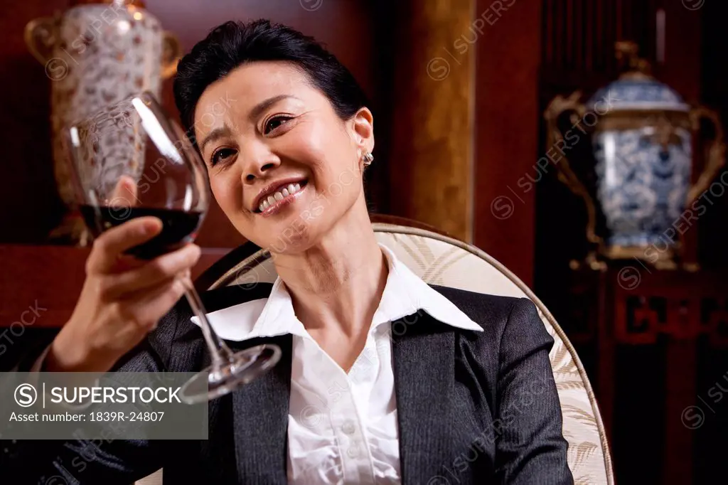 Mature businesswoman enjoying wine in a luxurious room