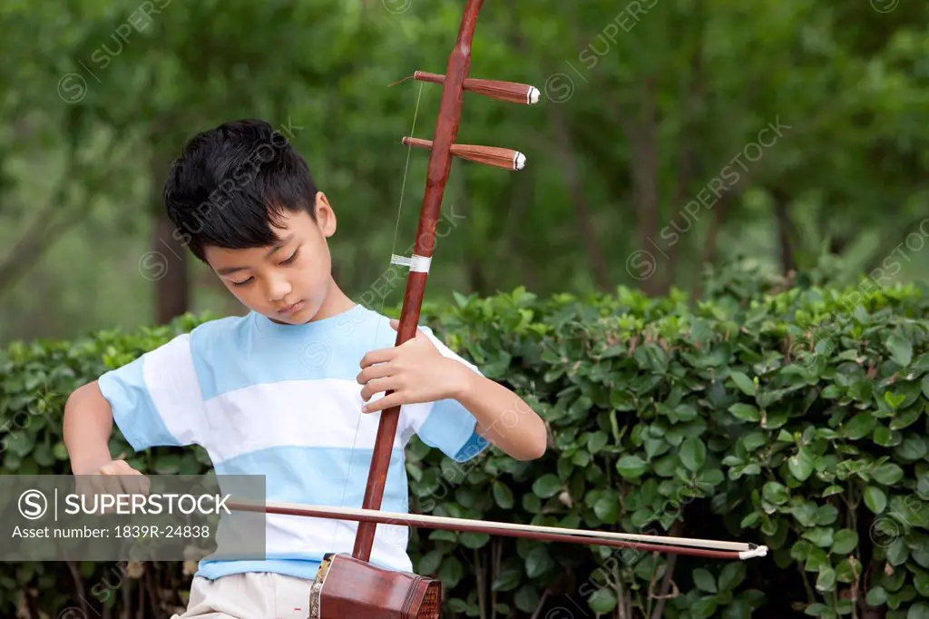 Boy playing Chinese traditional musical instrument Erhu