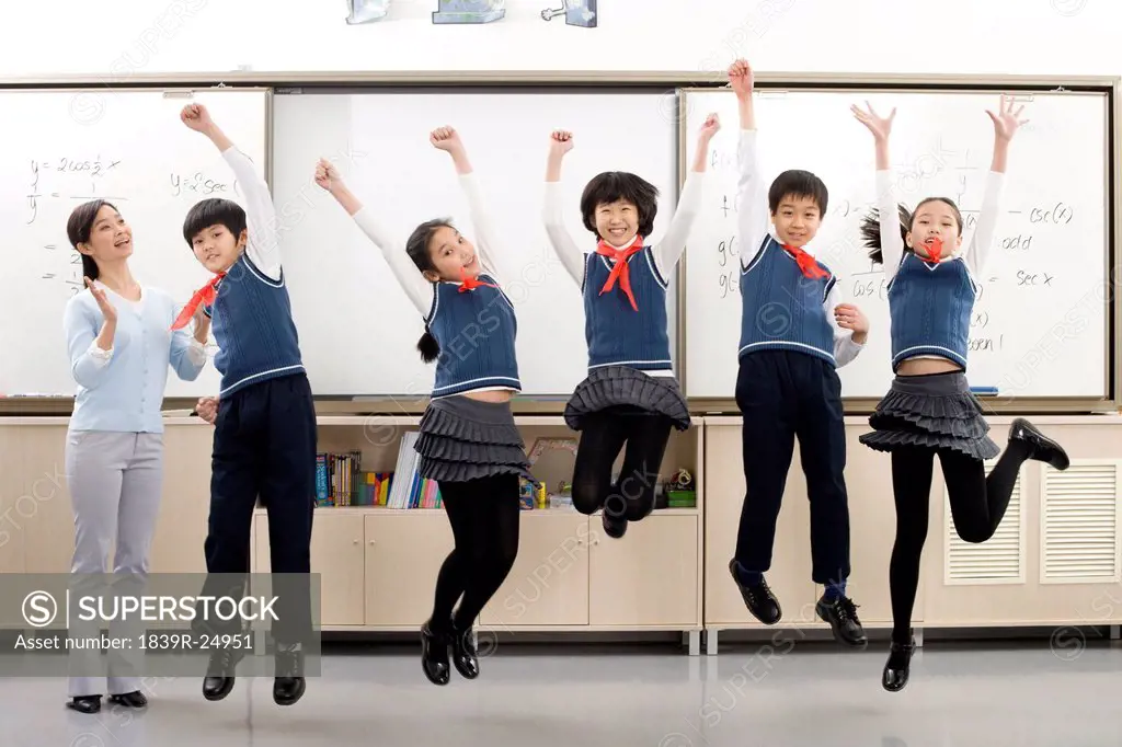 Young students jumping in front of whiteboard