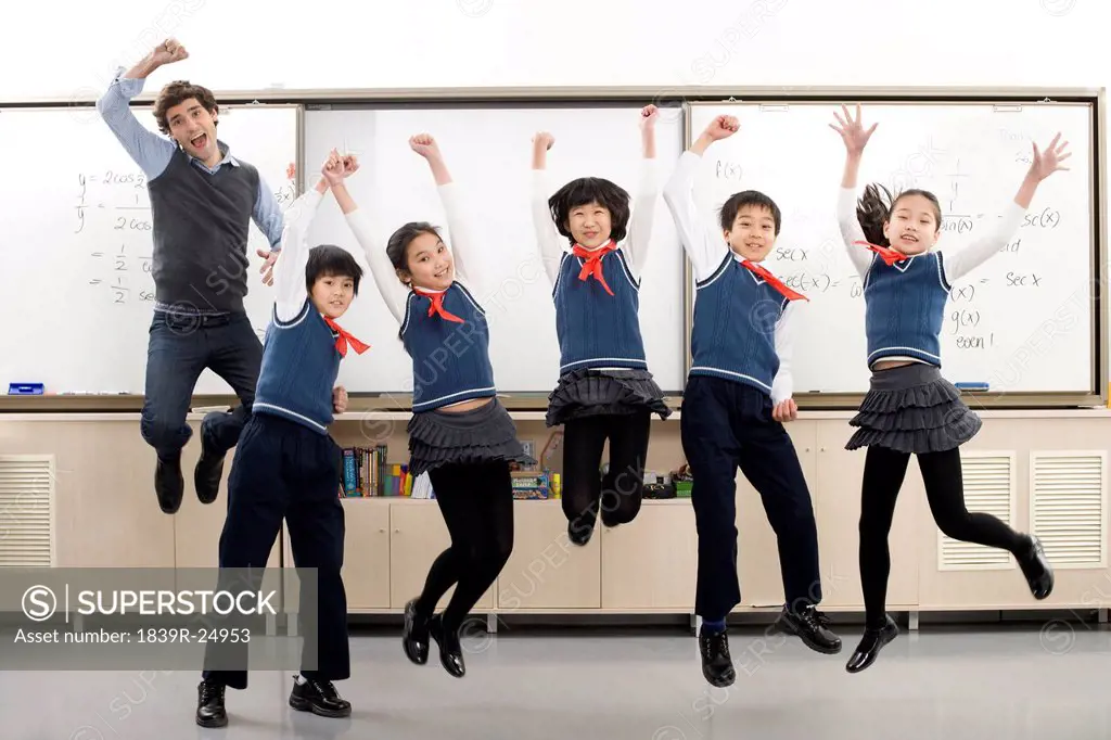 Teacher and students jumping in front of whiteboard