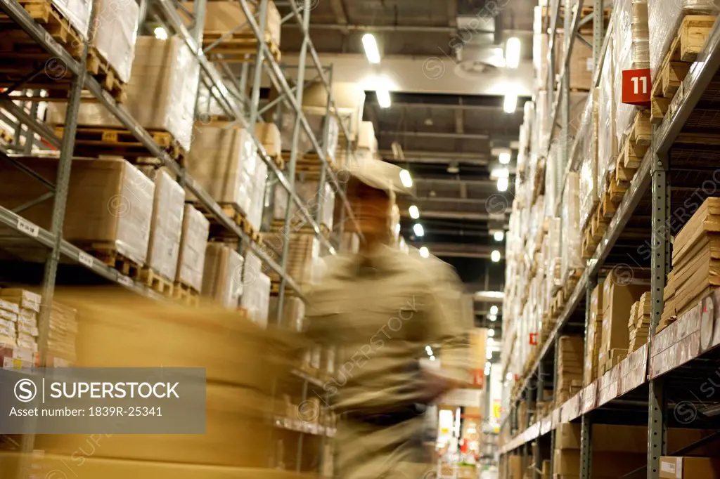 Blurred motion shot of Chinese warehouse worker pushing boxes