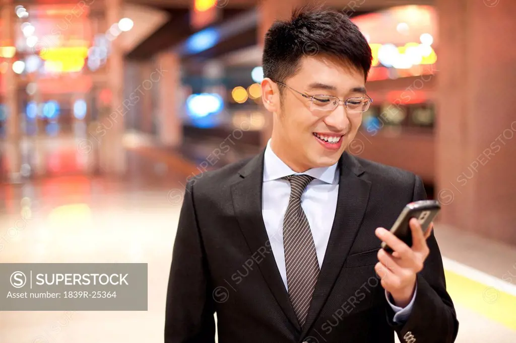 Young businessman using his mobile phone at the train station