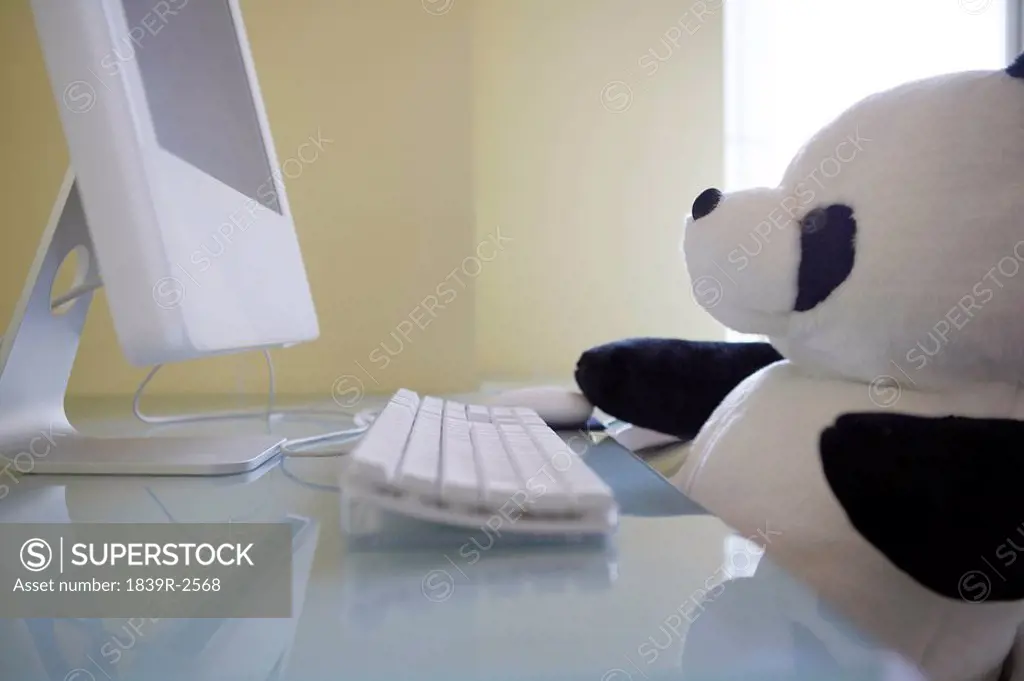Soft Toy Panda Sitting In Front Of Computer
