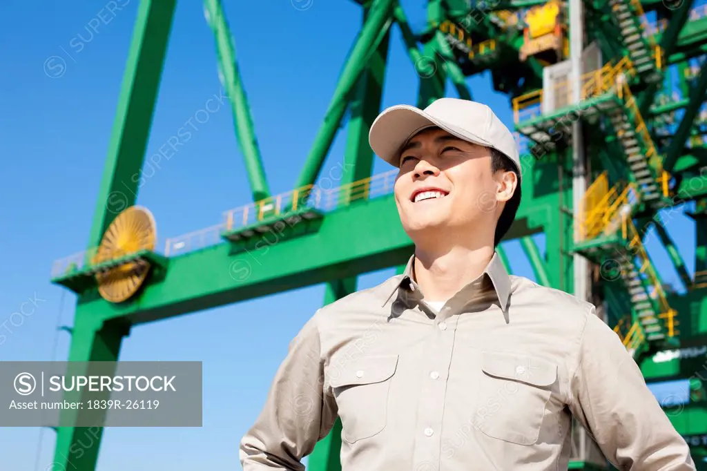Male shipping industry worker with crane in the background
