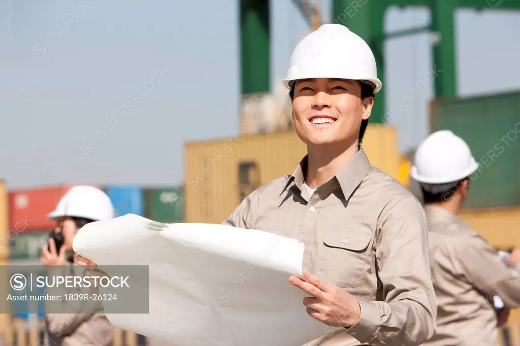 Male shipping worker checking blueprints