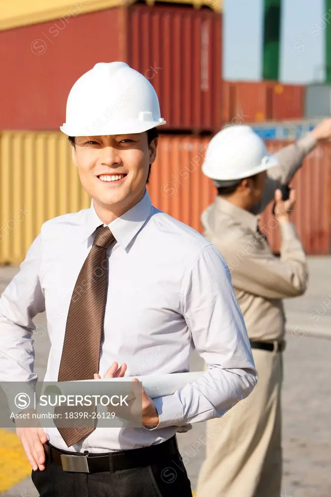 businessman with blueprints and shipping industry worker using his walkie_talkie