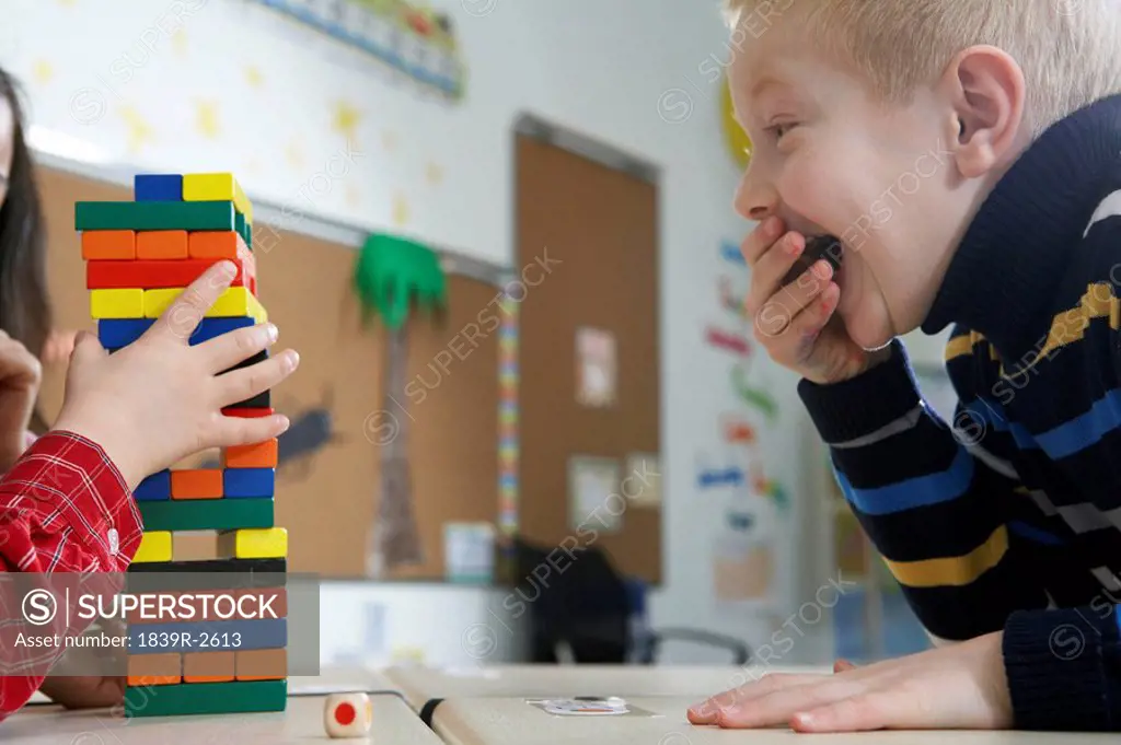 Boy Looking At Tower Of Blocks And Laughing