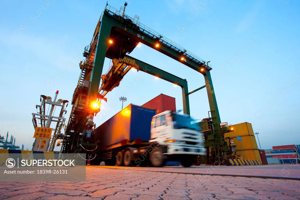 Blurred motion of truck with cargo containers and cranes in a shipping port