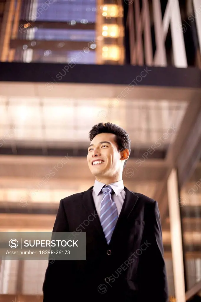 A businessman outside an office building at night