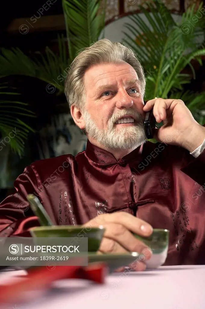 Man Talking On Cellphone At Dinner Table