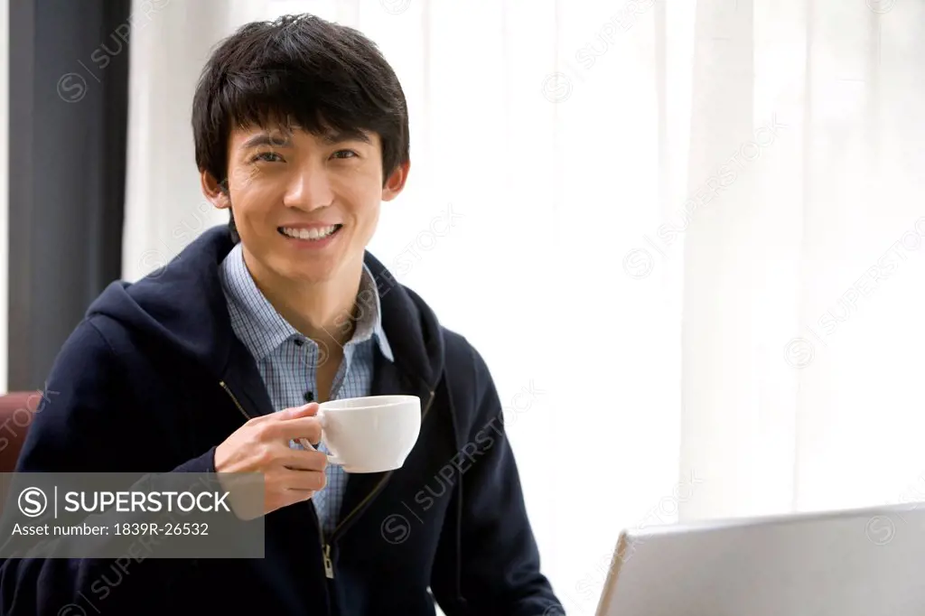 A young man smiling while enjoying coffee at a cafe