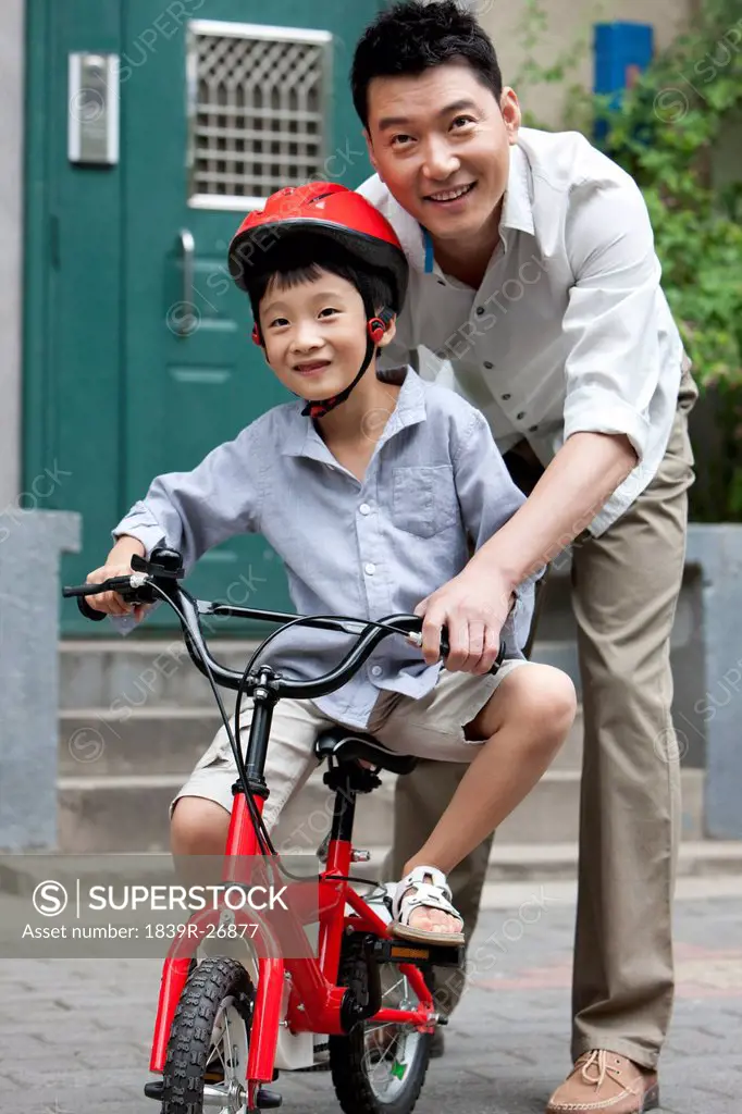Young Chinese father training son to ride a bike