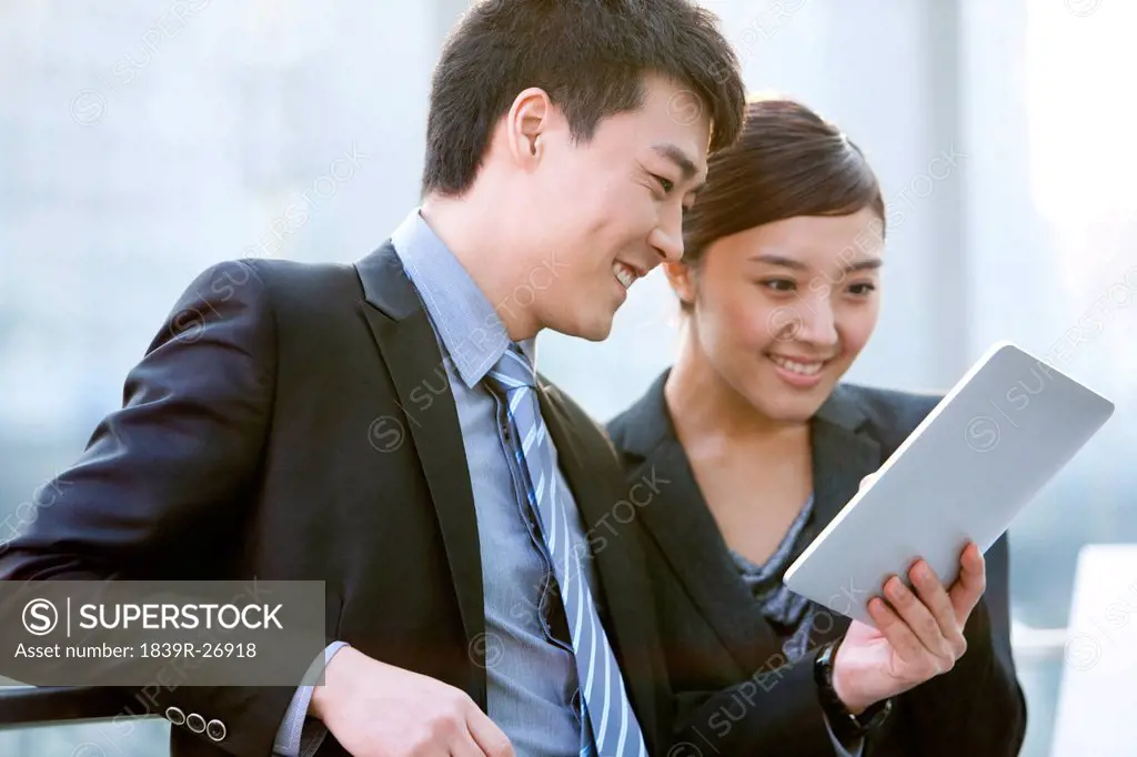 Chinese businessman and businesswoman using digital tablet