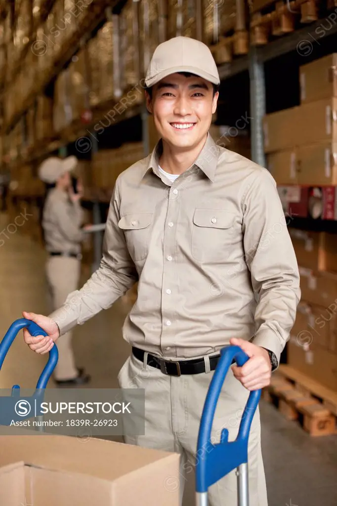 Male Chinese warehouse worker pushing boxes