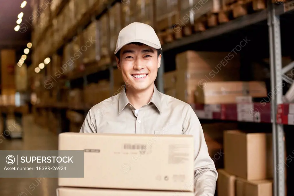 Male Chinese warehouse worker carrying boxes