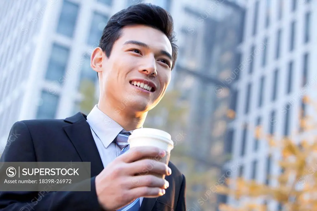 Businessman outside office buildings holding a cup of coffee