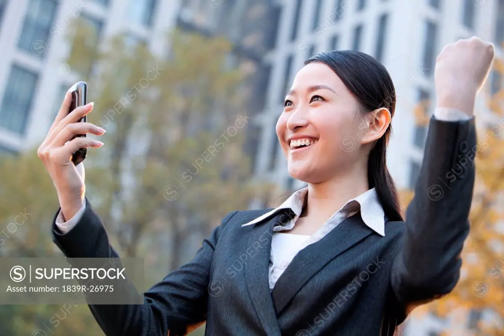 Businesswoman looking at her mobile phone and celebrating